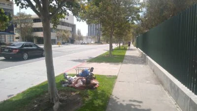 Homeless sleeping next to the street, while car is passing by