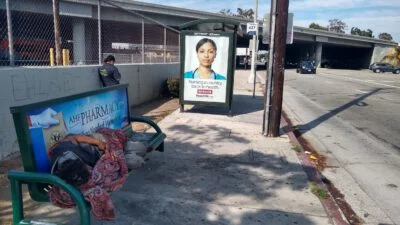 Homeless sleeping next to the street on a bench